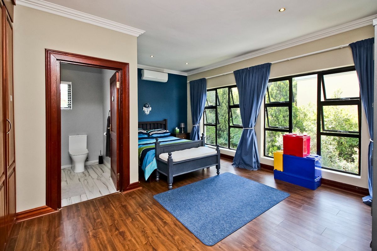 Spacious bedroom featuring laminate flooring, large windows with natural light, recessed lighting, and an attached en-suite bathroom with modern fixtures.