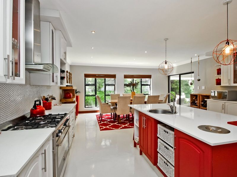 Spacious open-plan kitchen and dining area featuring a central island, modern gas cooktop, sleek cabinetry, and large sliding doors leading to the garden.