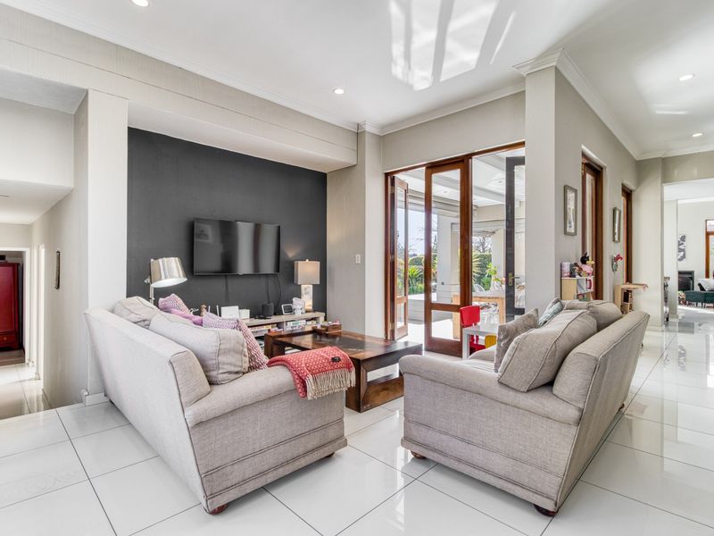 Spacious living room featuring polished tiled floors, a dark accent wall, and timber-framed glass doors providing seamless access to the outdoor patio area.