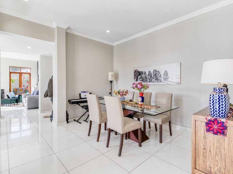 Bright dining area featuring polished porcelain floor tiles, crown molding, and recessed lighting, with an open-plan flow into the adjacent living space.