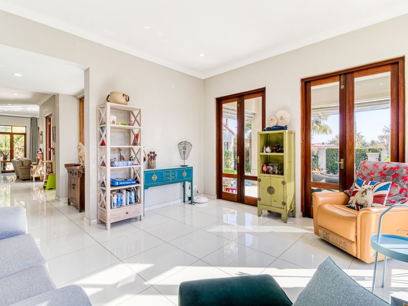 Bright and spacious living area featuring polished tiled flooring, recessed lighting, and large wooden-framed glass doors providing seamless access to the outdoor patio.