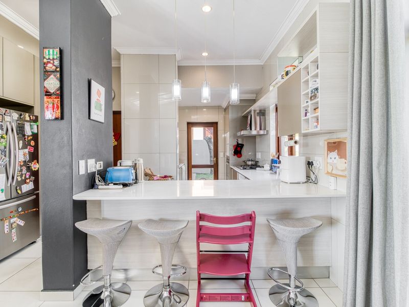 Modern kitchen featuring a breakfast bar, stone countertops, ample built-in cabinetry, and stainless steel appliances, with a clean, functional layout.