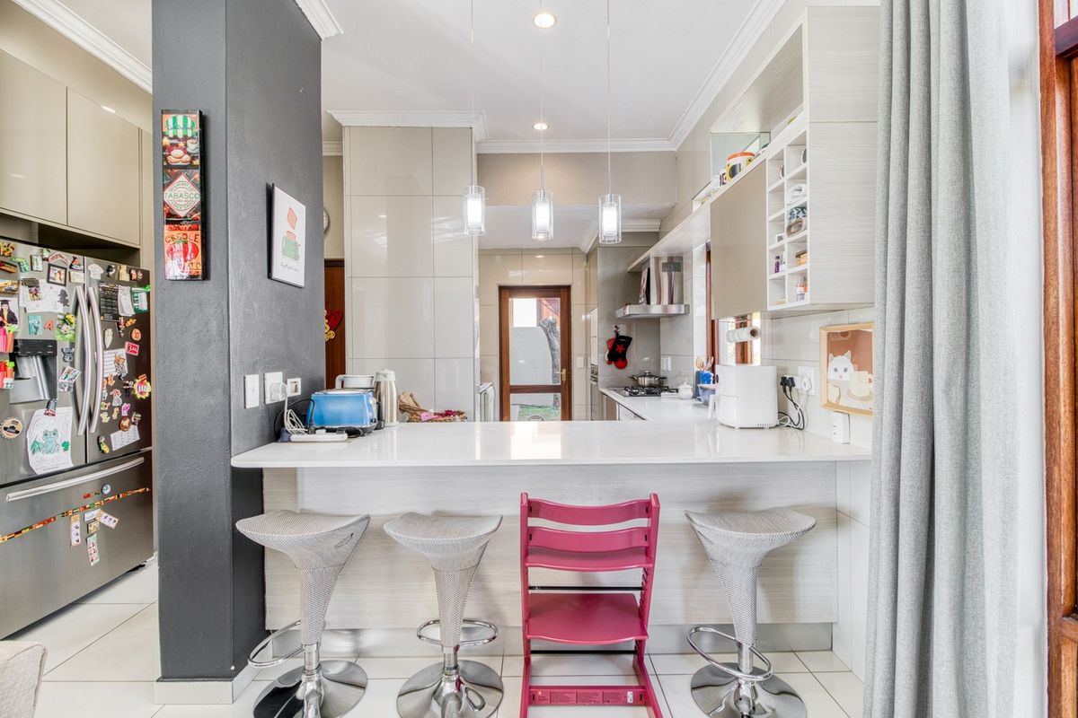 Modern kitchen featuring a breakfast bar, stone countertops, ample built-in cabinetry, and stainless steel appliances, with a clean, functional layout.