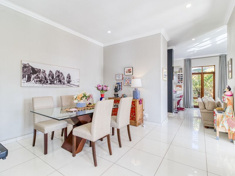 Bright open-plan dining area featuring polished porcelain floor tiles, recessed downlighting, and seamless flow to the adjacent living space and outdoor access.