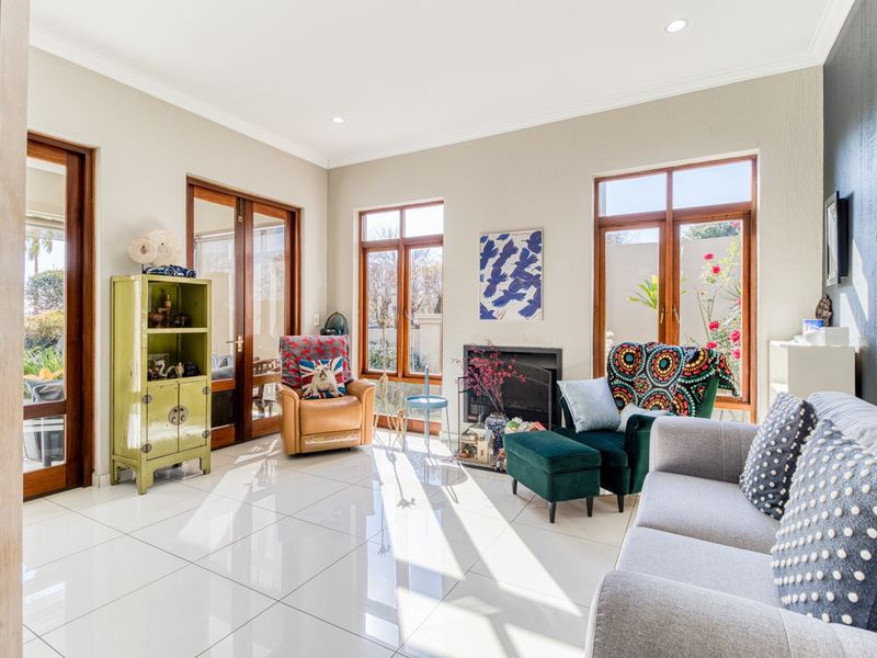 Bright and spacious living room featuring polished tiled floors, a built-in fireplace, and large wooden-framed glass doors providing natural light and garden access.