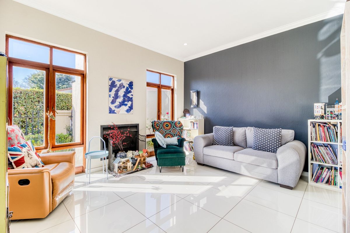 Bright living room featuring large timber-framed windows, polished tiled flooring, a built-in fireplace, and a striking dark feature wall.