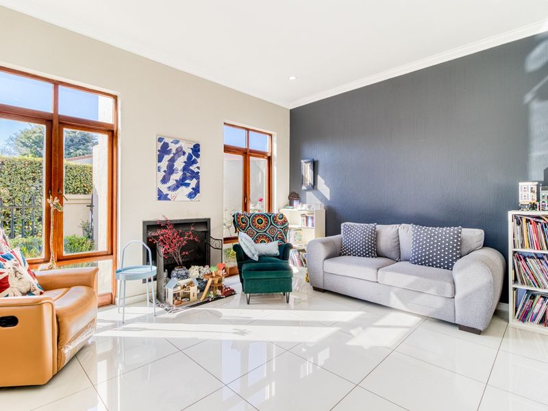 Bright living room featuring large timber-framed windows, polished tiled flooring, a built-in fireplace, and a striking dark feature wall.