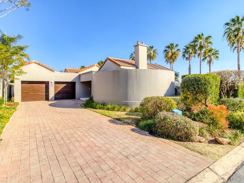 Front elevation of a house featuring a paved driveway, double garage, and well-maintained landscaped garden.