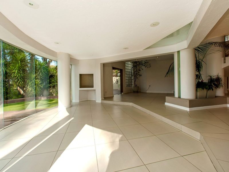 Spacious, light-filled living area featuring large curved glass windows, tiled flooring, and a unique architectural layout with a built-in wall niche.