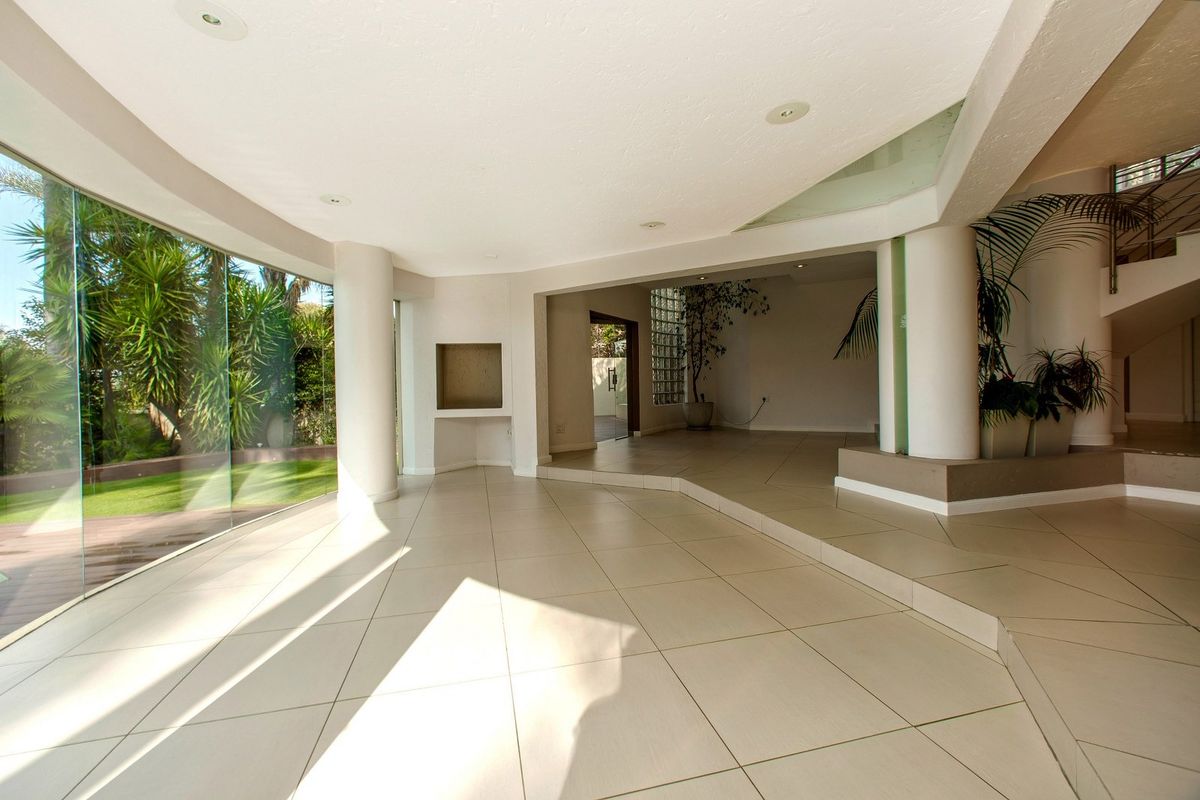 Spacious, light-filled living area featuring large curved glass windows, tiled flooring, and a unique architectural layout with a built-in wall niche.