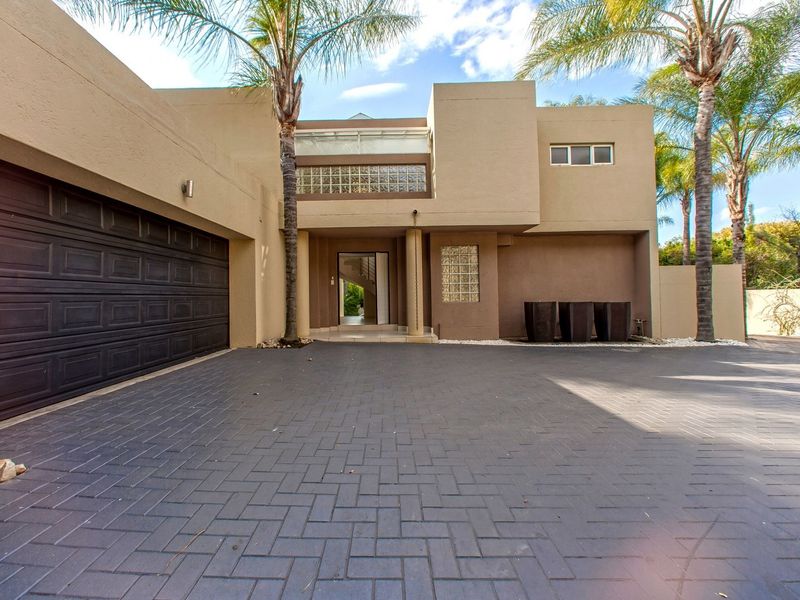 Modern double-story residence featuring a paved driveway, integrated double garage, and a distinctive glass block architectural detail at the main entrance.