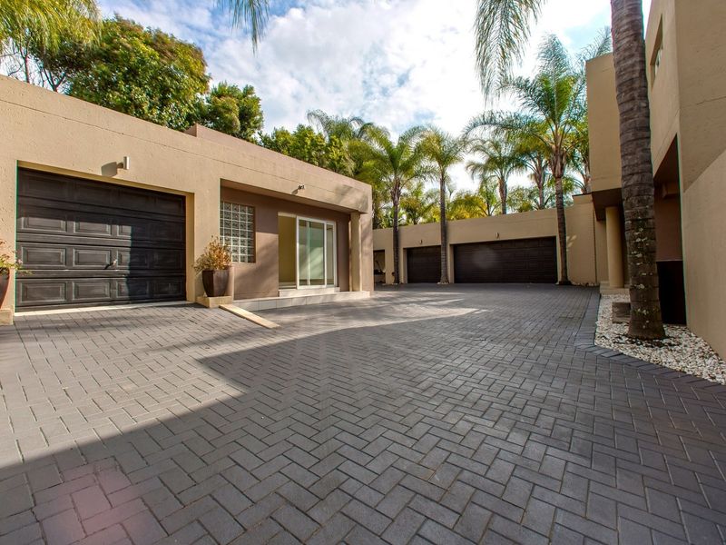 Spacious paved driveway leading to multiple garage doors and a modern entrance with glass block detailing and sliding door access.
