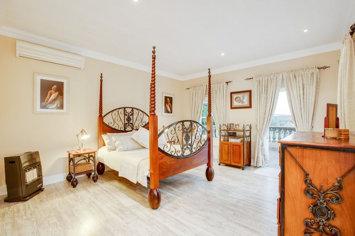 Spacious bedroom featuring light-toned laminate flooring, recessed downlighting, crown molding, and direct access to a private balcony through a glass door.