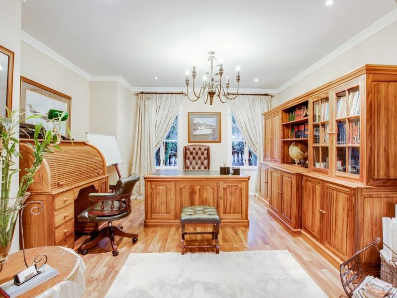 A well-appointed home office featuring hardwood flooring, crown molding, and elegant lighting, providing a professional and comfortable workspace.