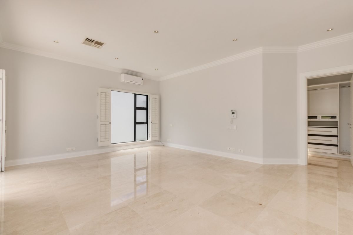 Spacious bedroom featuring polished marble flooring, recessed lighting, plantation shutters, and a walk-in closet with built-in cabinetry.