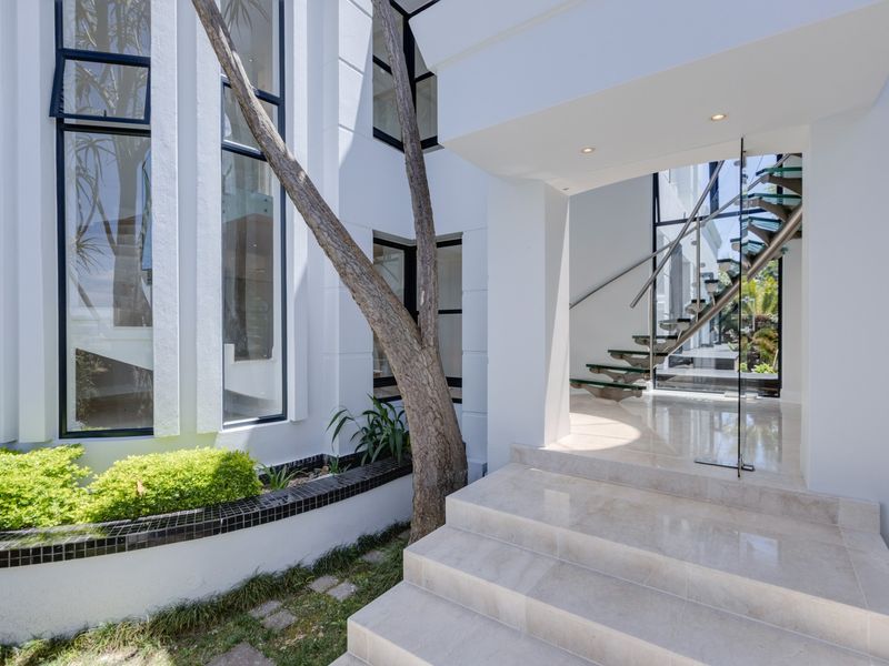 Modern entrance featuring a striking glass staircase, polished tiled steps, and expansive floor-to-ceiling windows that create a bright and architectural aesthetic.