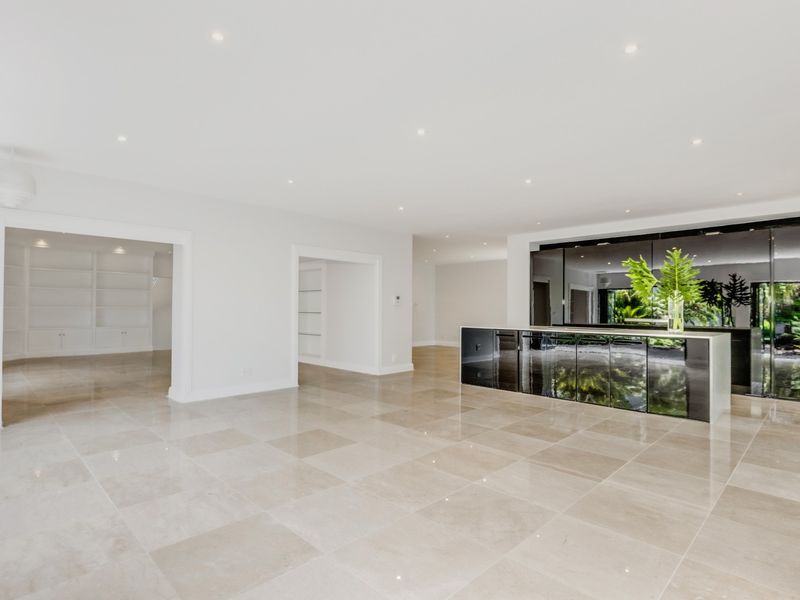 Spacious open-plan living area featuring polished stone flooring, recessed lighting, and a sleek, modern integrated kitchen with high-gloss cabinetry.