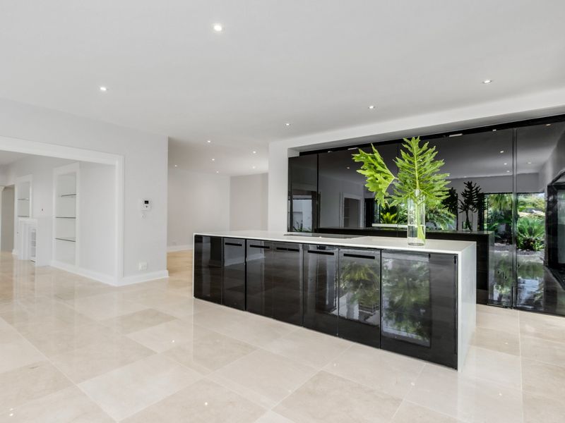 Modern kitchen featuring a sleek black island with stone countertop, high-gloss cabinetry, and polished tile flooring in an open-plan layout.