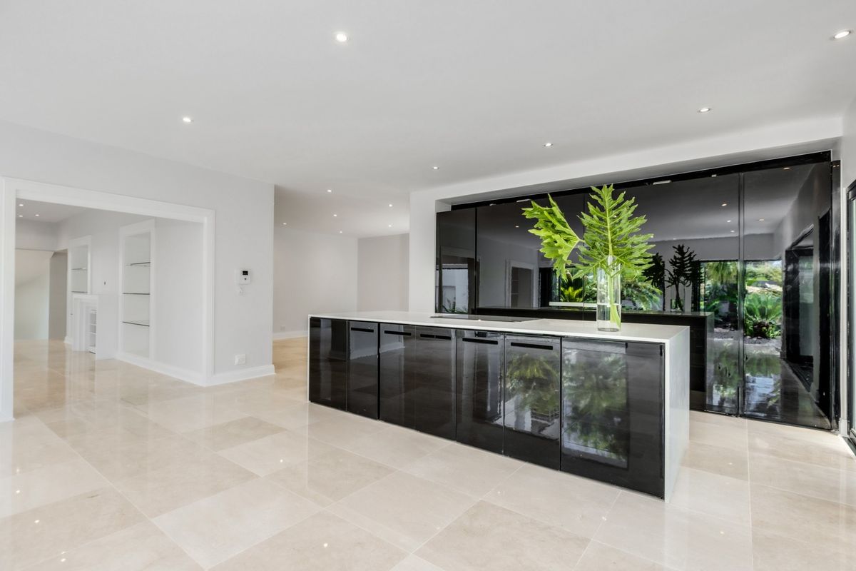 Modern kitchen featuring a sleek black island with stone countertop, high-gloss cabinetry, and polished tile flooring in an open-plan layout.