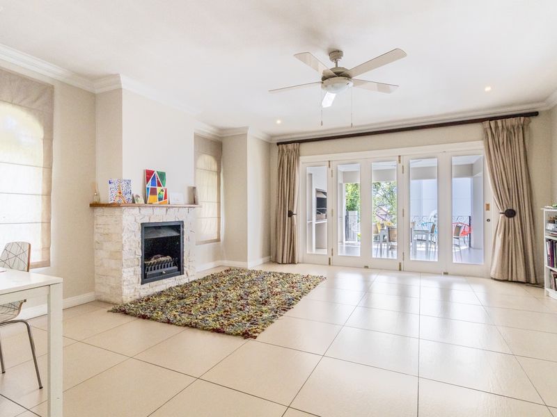Spacious living room featuring tiled flooring, a stone-clad fireplace, and large glass french doors providing natural light and access to the patio.