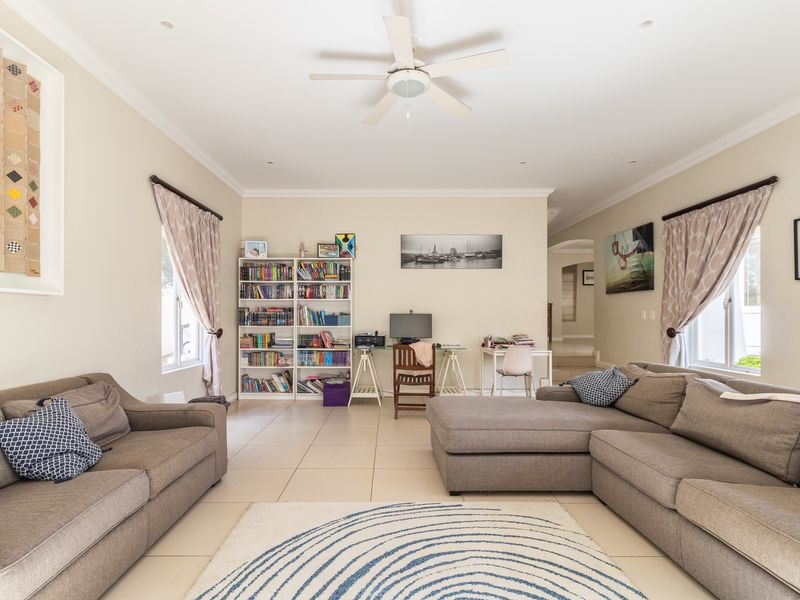 A spacious living room featuring neutral tiled flooring, recessed lighting, and a ceiling fan, offering a comfortable and well-maintained living area.