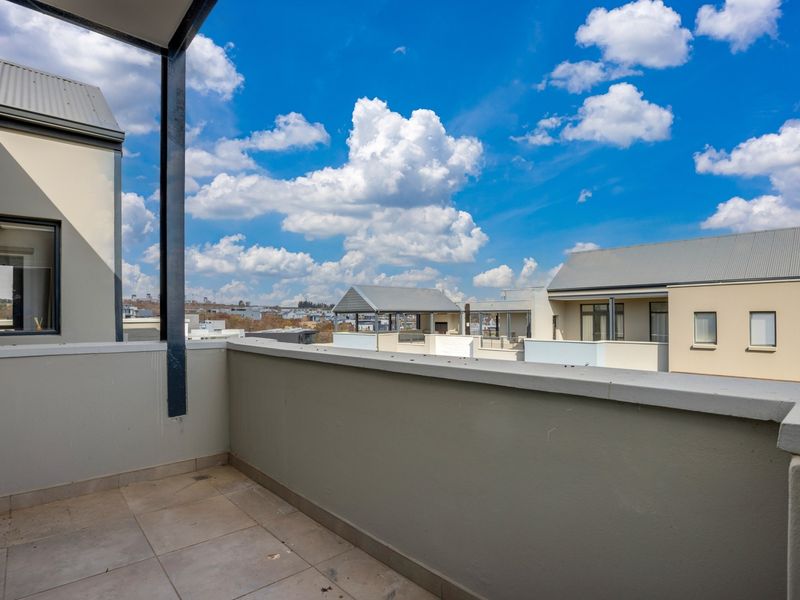 A spacious open-air balcony featuring tiled flooring and a solid parapet wall, offering clear views of the surrounding residential complex.