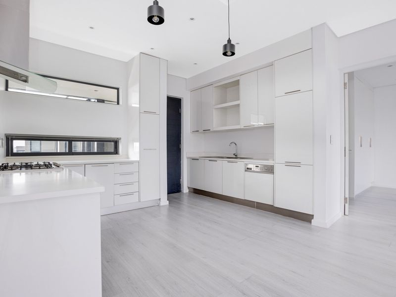Modern, minimalist kitchen featuring sleek white cabinetry, integrated appliances, gas hob, and high-quality finishes in a bright, open-plan layout.