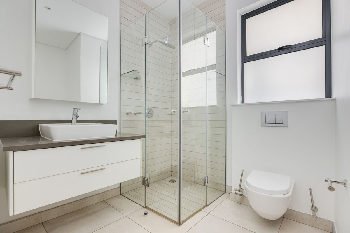 Modern bathroom featuring a glass-enclosed shower, wall-mounted vanity with a countertop basin, and a sleek wall-hung toilet with a concealed cistern.