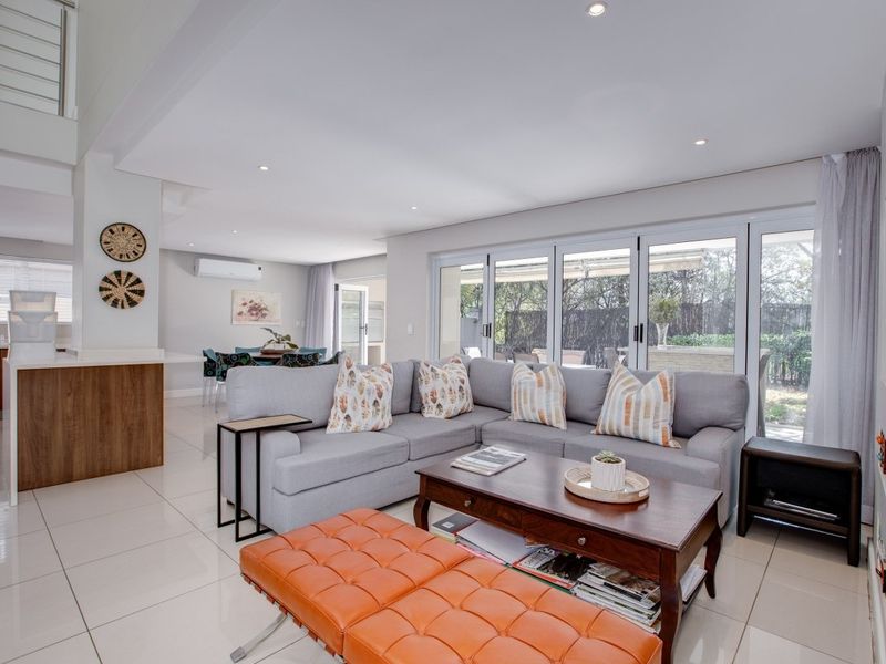 Spacious open-plan living area featuring tiled floors, recessed lighting, and large sliding glass doors that provide seamless access to the outdoor patio area.