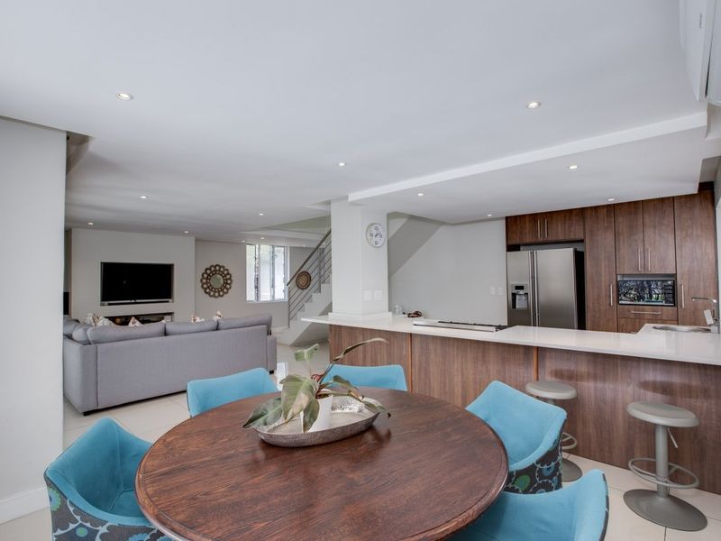 Spacious open-plan living area featuring a modern kitchen with wood-finish cabinetry, stone countertops, and seamless flow to the dining and lounge spaces.