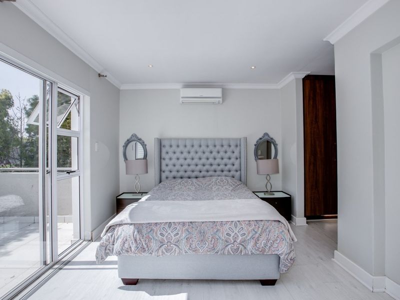A well-maintained bedroom featuring built-in cupboards, air conditioning, and a sliding glass door providing access to an outdoor balcony.