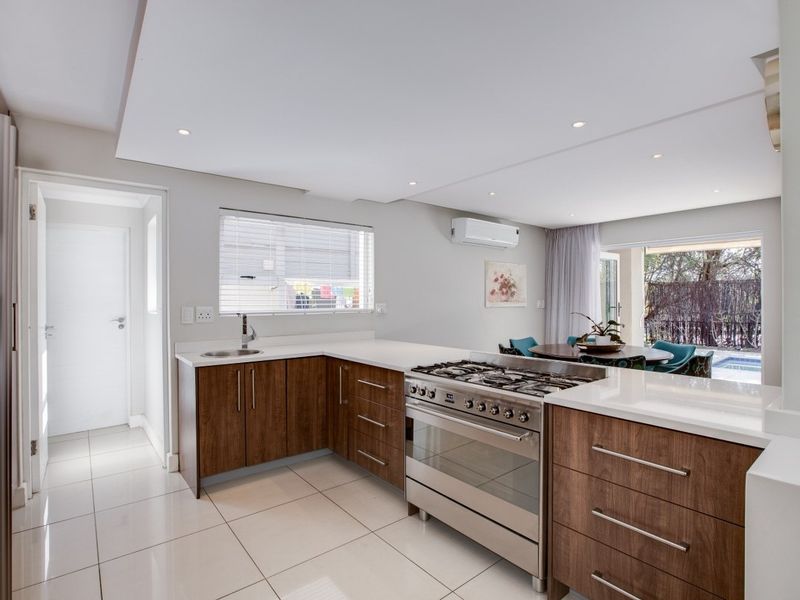 Modern open-plan kitchen featuring wood-finish cabinetry, stone countertops, a gas stove, and direct access to the outdoor patio area.
