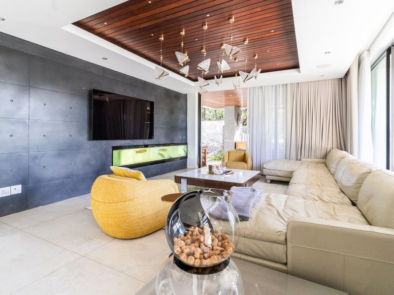 Modern living room featuring a striking timber-paneled recessed ceiling, a dark feature wall with an integrated aquarium, and large sliding doors opening to the outdoors.