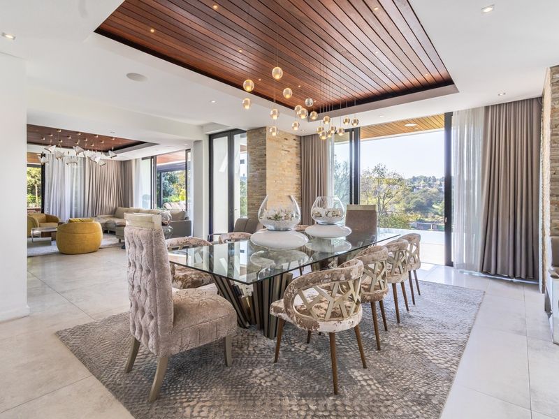 Spacious open-plan dining and living area featuring a striking timber-clad recessed ceiling, stone feature wall, and large sliding doors opening to an outdoor view.