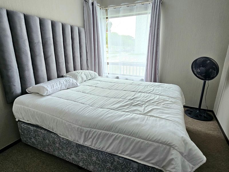A bedroom featuring carpeted flooring and a window with curtains, providing a functional space for rest.