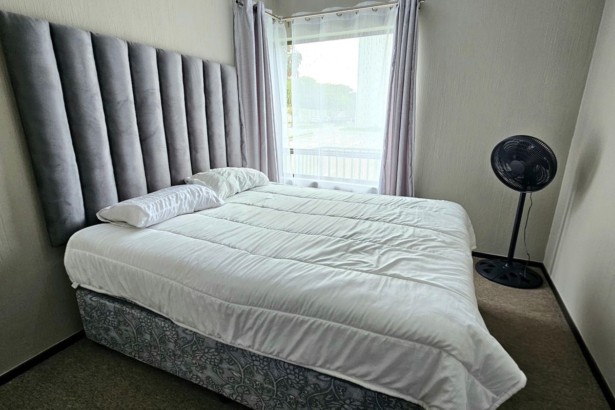 A bedroom featuring carpeted flooring and a window with curtains, providing a functional space for rest.