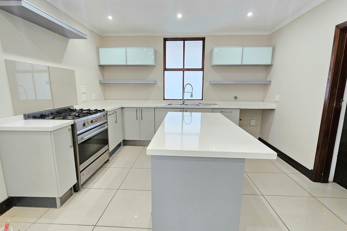 Modern kitchen featuring a central island, quartz countertops, gas stove with extractor, and ample built-in cabinetry with a clean, neutral aesthetic.