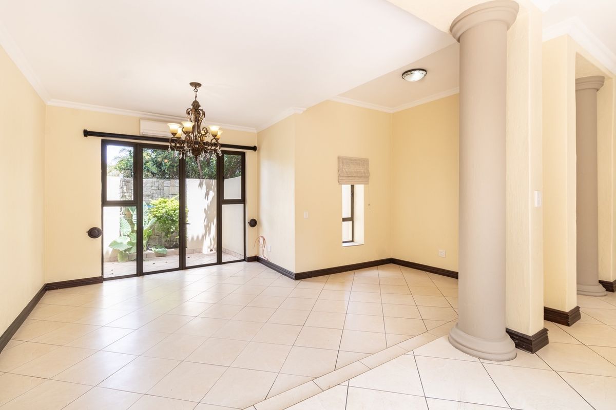 Spacious living area featuring ceramic tile flooring, decorative columns, and sliding glass doors providing access to the outdoor space.