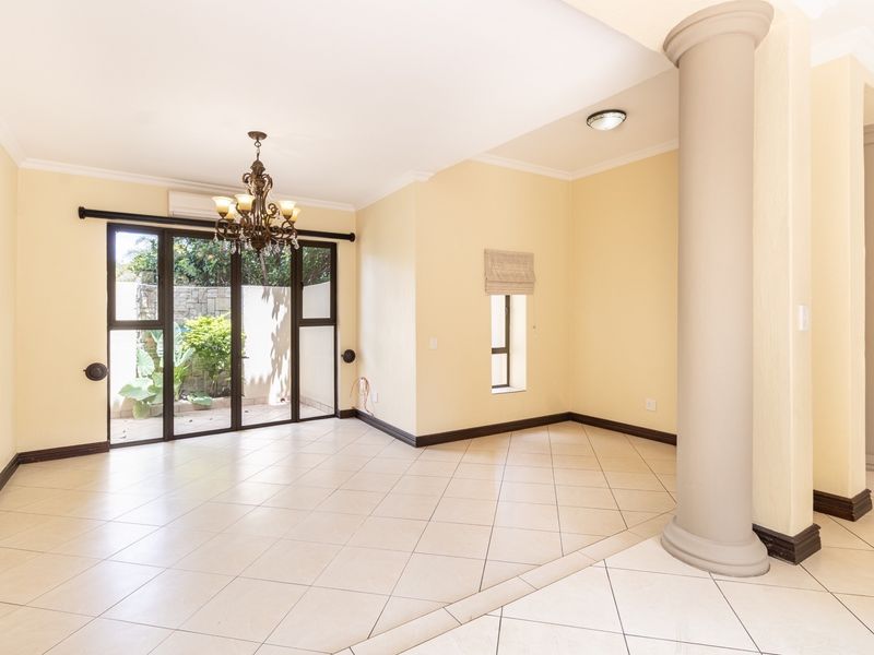 Spacious living area featuring ceramic tile flooring, decorative columns, and sliding glass doors providing access to the outdoor space.