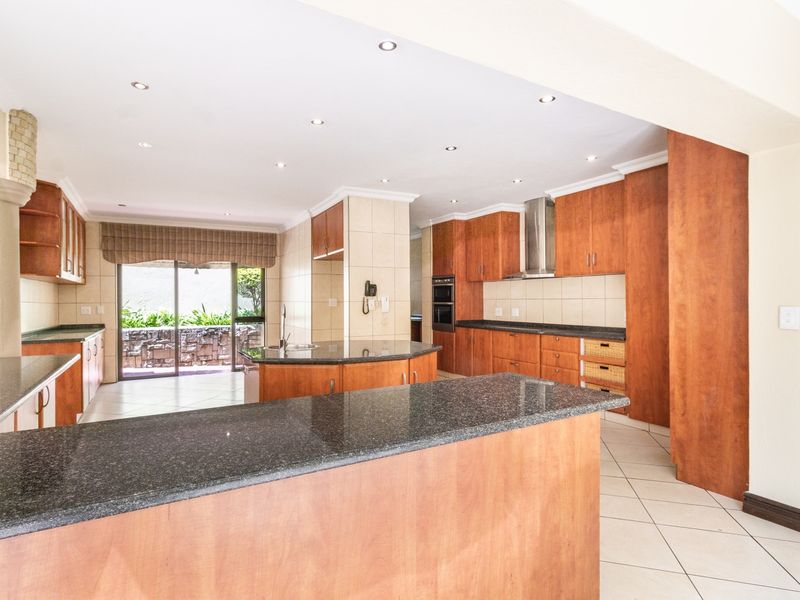 Spacious kitchen featuring extensive wooden cabinetry, granite countertops, built-in oven, and direct access to an outdoor patio area.