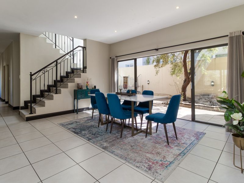 Spacious dining area featuring tiled flooring, a wrought iron staircase, and large sliding glass doors providing natural light and access to the patio.