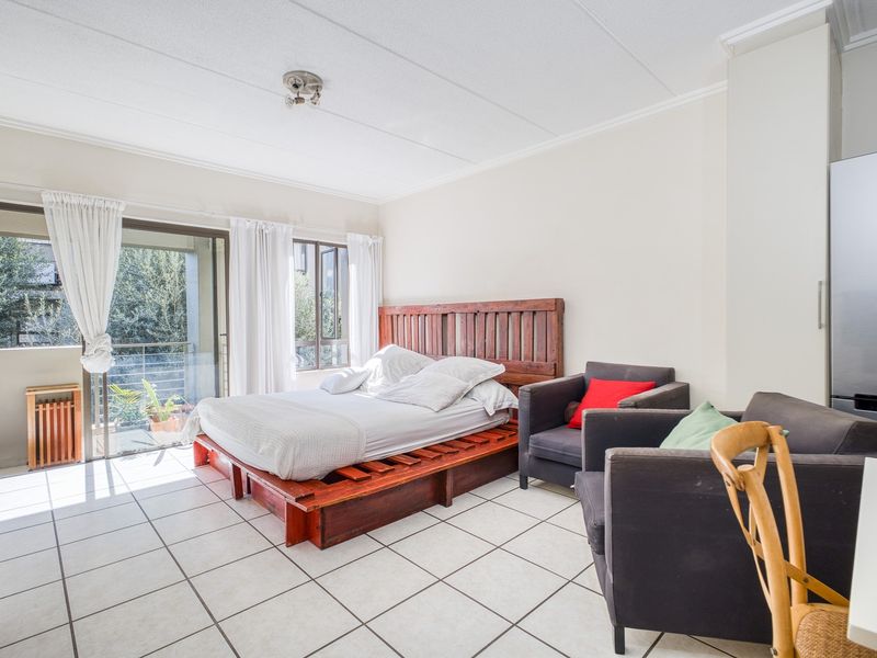 Spacious bedroom featuring tiled flooring, built-in storage, and a sliding glass door providing access to a private balcony with natural light.