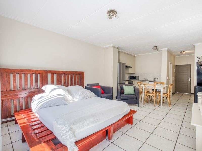 Open-plan studio apartment featuring a combined living and sleeping area with an adjoining kitchenette, tiled flooring, and neutral wall finishes.