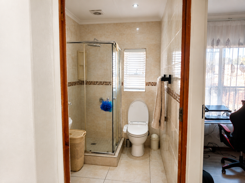 A functional bathroom featuring a glass-enclosed shower, tiled walls and flooring, and modern fixtures, providing a clean and well-maintained space.