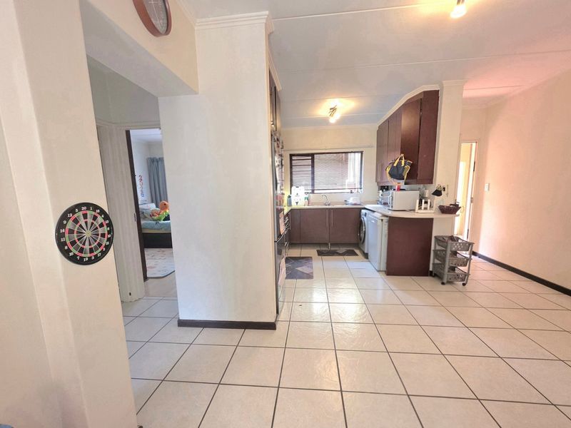 Open plan living area featuring tiled flooring and a functional kitchen with built-in cabinetry and laundry plumbing connections.