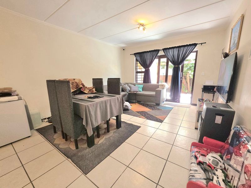 An open-plan living and dining area featuring tiled flooring and a sliding glass door providing access to the exterior.