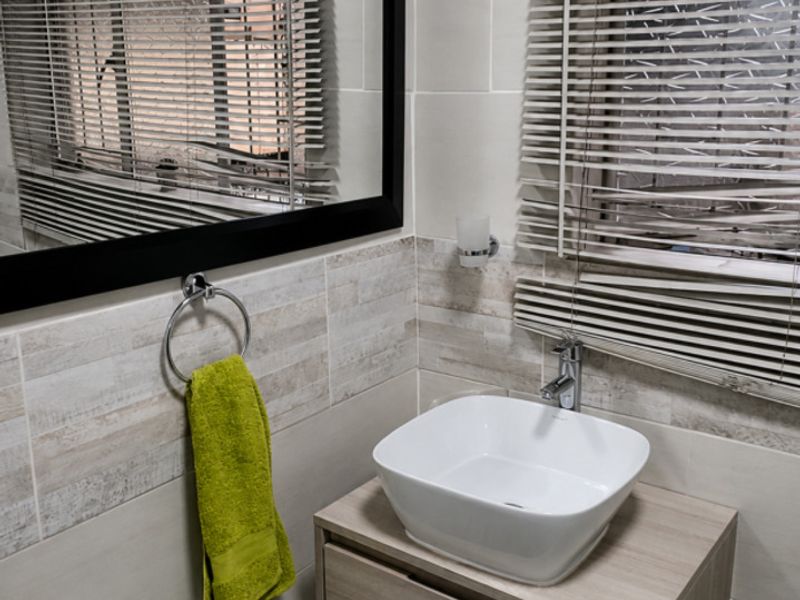 Modern bathroom featuring a wall-mounted vanity with a contemporary vessel sink, chrome fixtures, and neutral wall tiling.