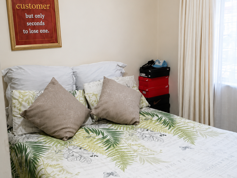 A functional bedroom featuring neutral wall finishes and a window with installed curtain rods.