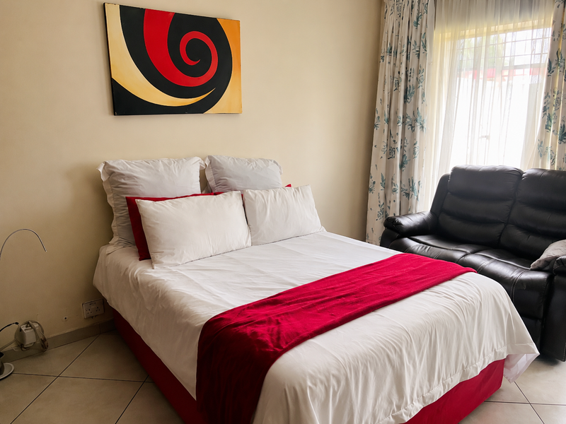 A well-lit bedroom featuring tiled flooring and large windows with installed curtain rails, providing a comfortable and functional living space.