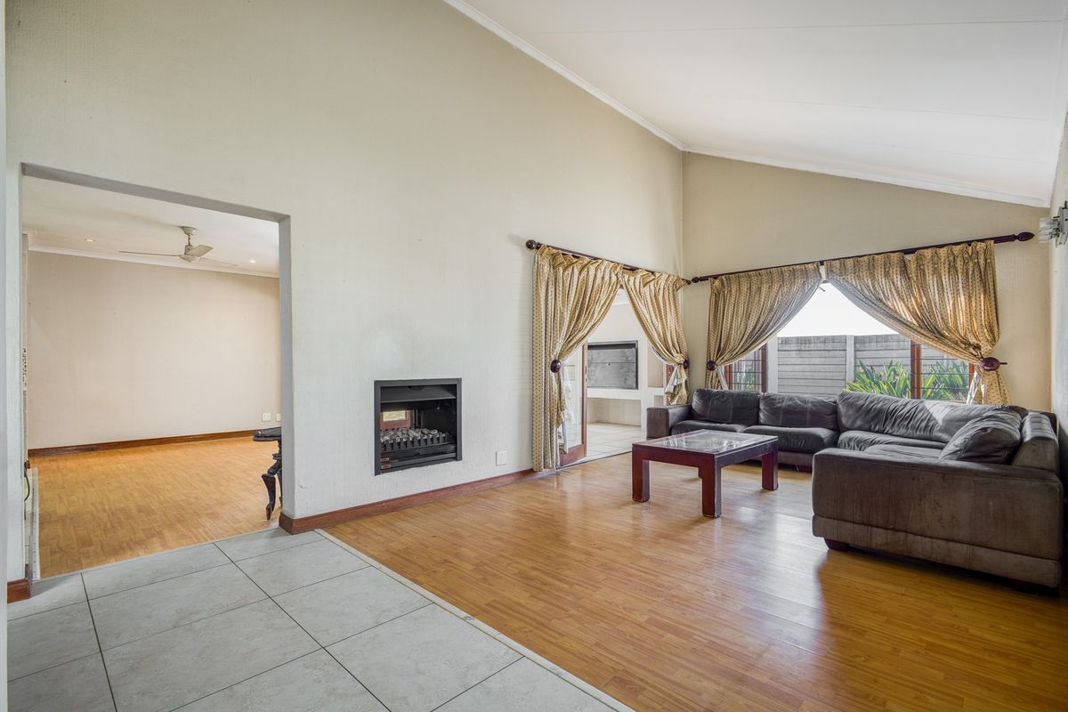 Spacious living room featuring a vaulted ceiling, built-in fireplace, and a mix of laminate and tiled flooring with access to an outdoor patio area.